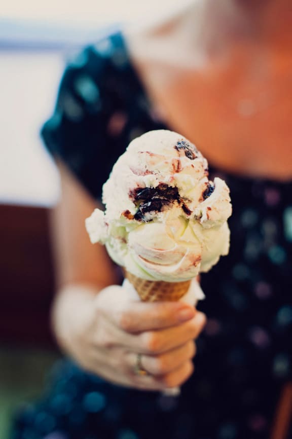 a woman holding up a cone of ice cream at 100 House Apartments, Jersey City , New Jersey