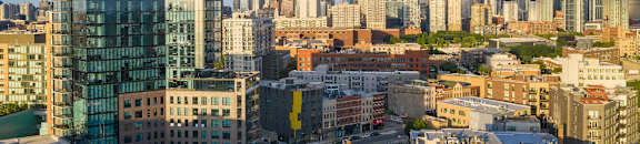 A cityscape with a mix of modern and older buildings under a partly cloudy sky.