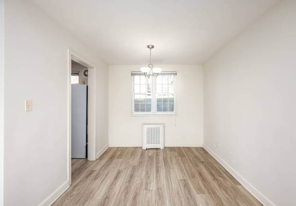 A room with a white door, a window with a white frame, and a white radiator.