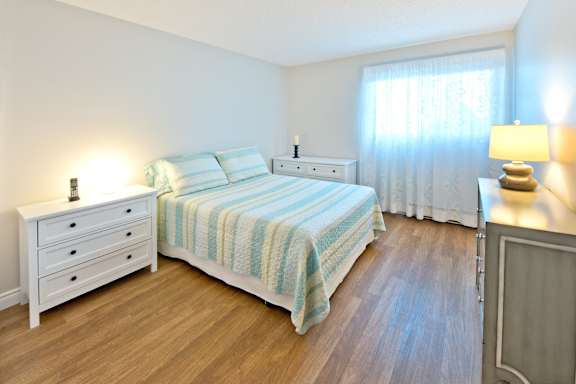 A bedroom with a bed, nightstand, and dresser.