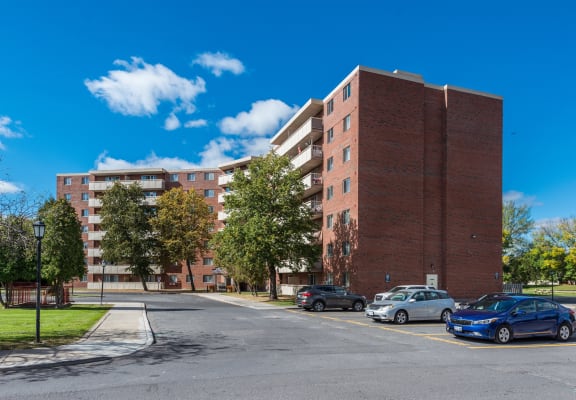 an empty street with cars parked in front of an apartment building