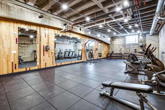 a gym with weights and other exercise equipments in a building with brick walls