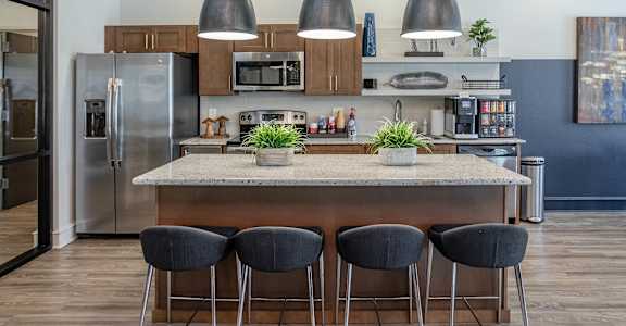a kitchen with a large island with four chairs at The McKenzie Park Apartments, Little Rock, 72223