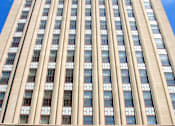 Thumbnail 22 of 23 - A tall building with a flag on top and a clear blue sky.