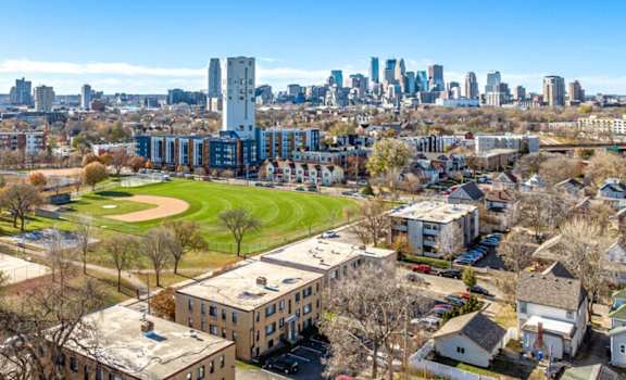 an aerial view of buildings and a park with a city in the background