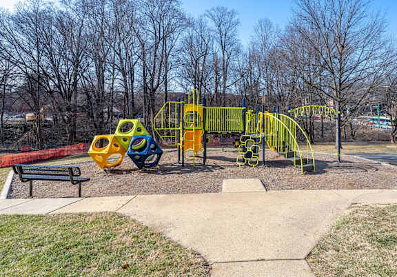 A playground with a yellow slide and a red bench.