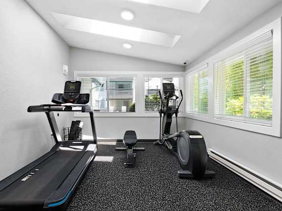 A treadmill and a stationary bike are in a well-lit room.