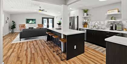 A modern kitchen with a bar area and a living room area.