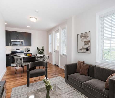 a living room with a couch and a chair and a kitchen with a dining room