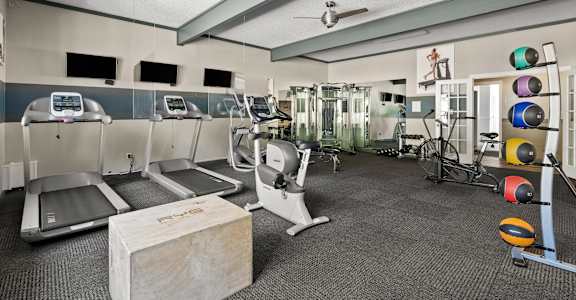 a gym with treadmills and weights and a table