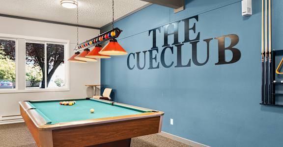 a pool table in a clubhouse with a blue wall