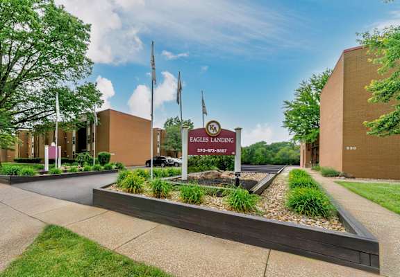 The image shows a well-maintained front yard of a building with a sign that reads "Eagles Landing."