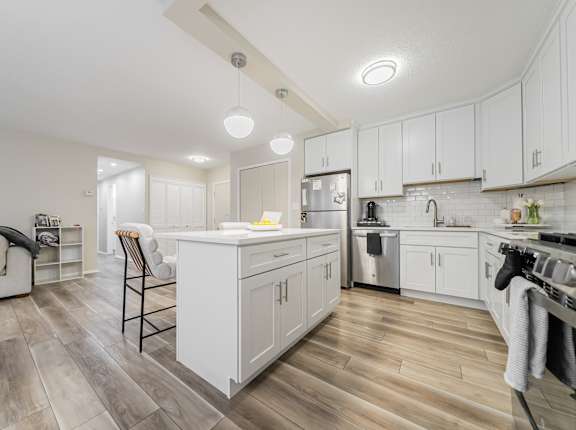 A modern kitchen with white cabinets and a wooden floor.
