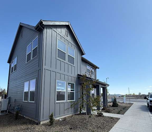 A modern house with a grey exterior and a gravel driveway.at Alante Homes at Spring Run, Caldwell