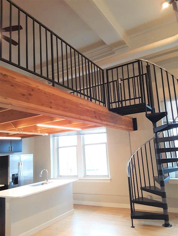 A spiral staircase with a black metal railing and wooden steps.