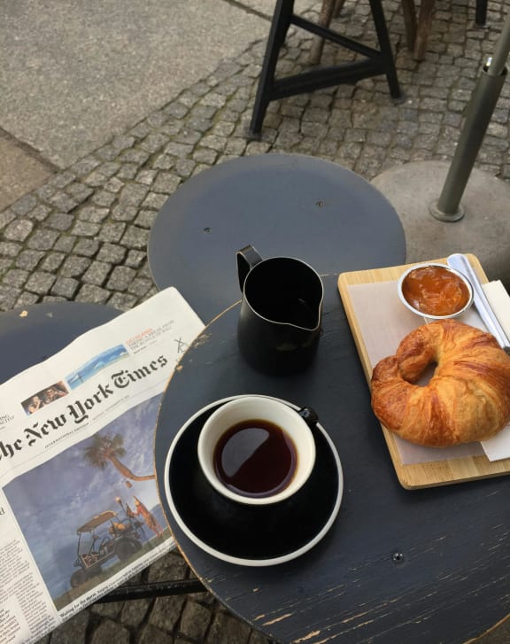 a cup of coffee and a croissant on a table