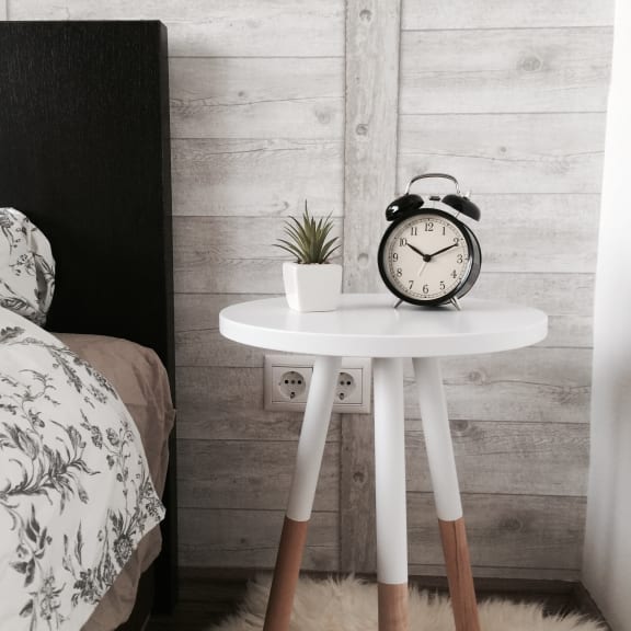 a bedside table with an alarm clock and a plant on it