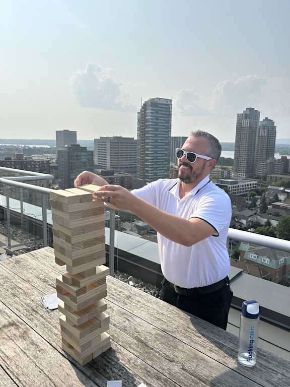 a man playing jigsaw puzzle on a balcony with a city in the background