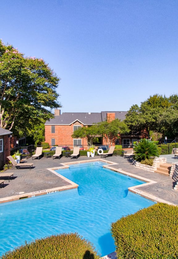 a swimming pool with lounge chairs and umbrellas in front of a house at Channings Mark, Austin, 78759