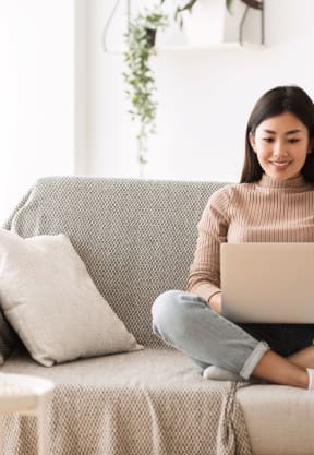 a woman sitting on a couch with her laptop at The District at Rosemary, Sarasota, FL, 34236