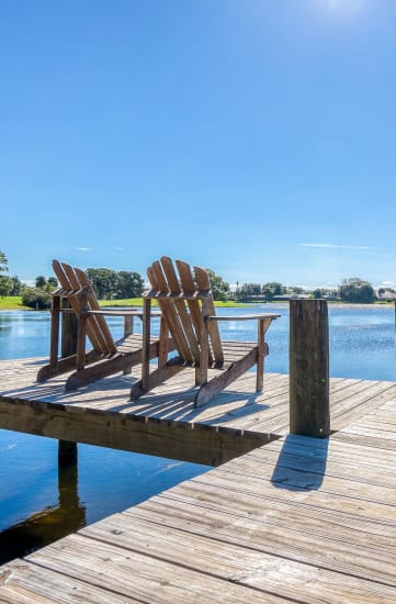 two adirondack chairs sit on the dock of a lake