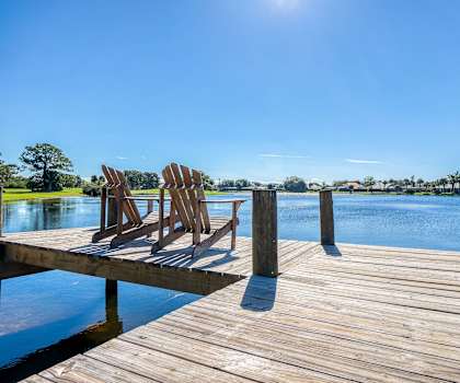 two adirondack chairs sit on the dock of a lake at Lakes at Suntree, Melbourne, Florida