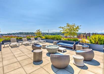 a roof terrace with chairs and tables overlooking a city
