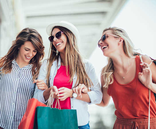 three women walking down the street with shopping bags at Cypress Gardens, Texas, 78613