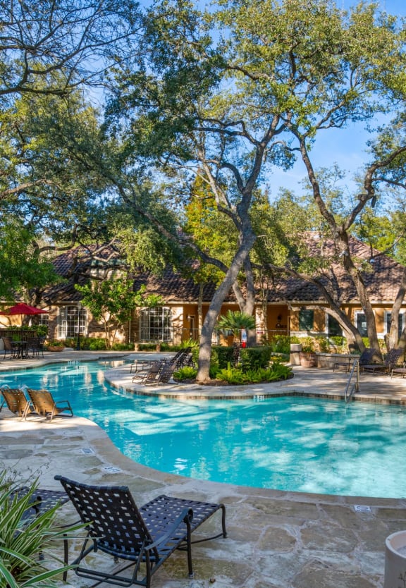 a swimming pool with trees and chairs around it at The Park at Monterey Oaks, Austin, TX