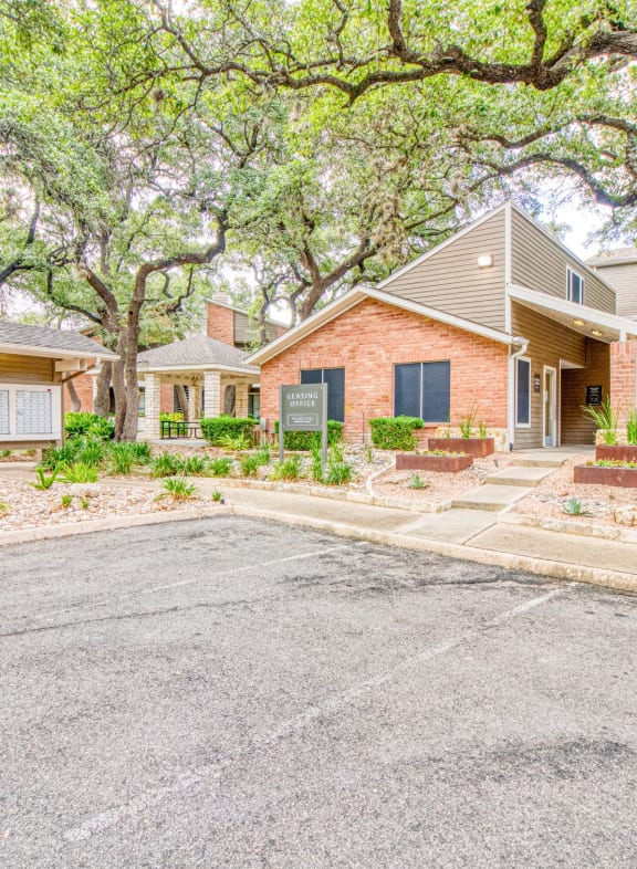 a house with a driveway and trees in front of it at Village Oaks Apartments, Austin, Texas