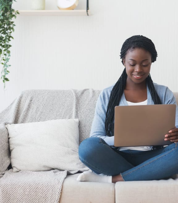 a woman sitting on a couch using a laptop computer at Highlands at Faxon Woods, Quincy, Massachusetts