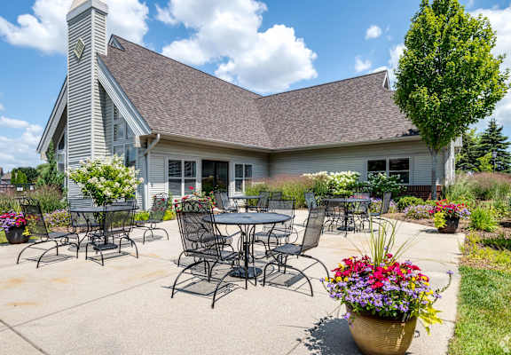 a patio with tables and chairs in front of a house