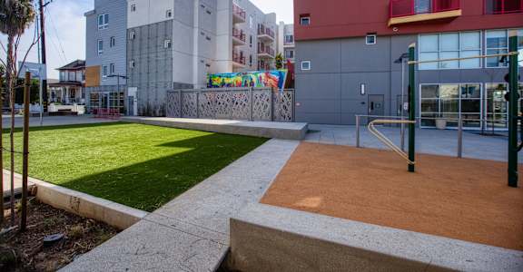 a courtyard between two buildings with grass and a playground