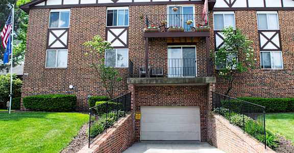 a brick apartment building with a garage door and a flag