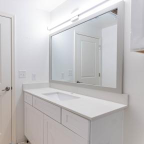 A white bathroom with a sink and mirror.