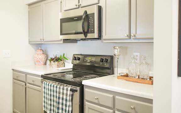a kitchen with white cabinets and a stove and microwave