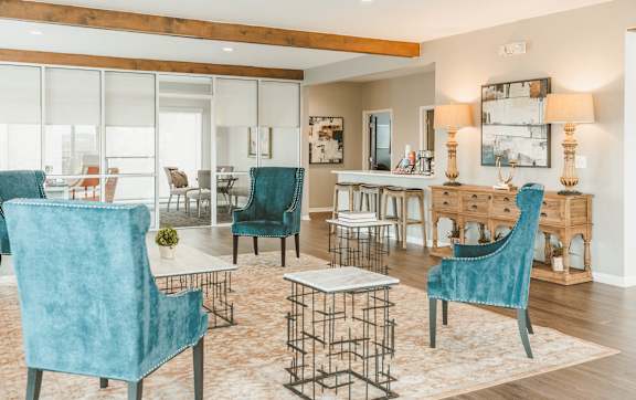 a living room with blue chairs and a dining table