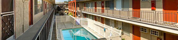 Apartments in Valley Village CA - Riverside Villa - Tan Building Exterior with View of Blue Pool and Poolside Area