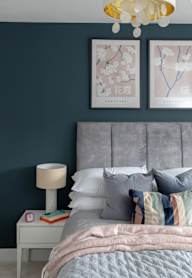 a bedroom with a bed and a nightstand with a lamp and a framed picture