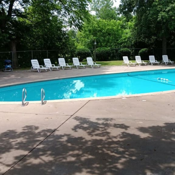 a swimming pool with chaise lounge chairs and trees in the background