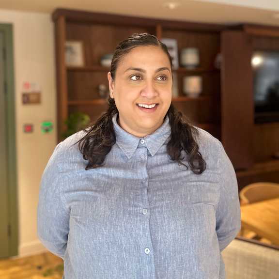 A woman with a blue shirt is standing in a room.