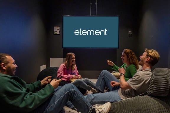 a group of people sitting on a couch in front of a screen with the word element on