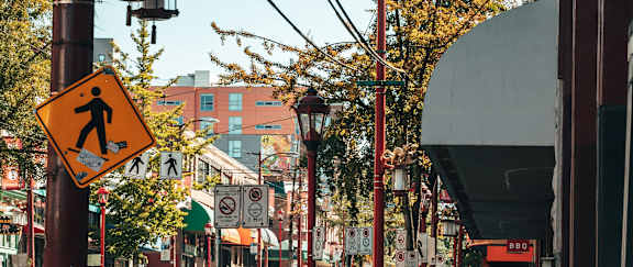 A pedestrian crossing sign is displayed on a pole in a city street.