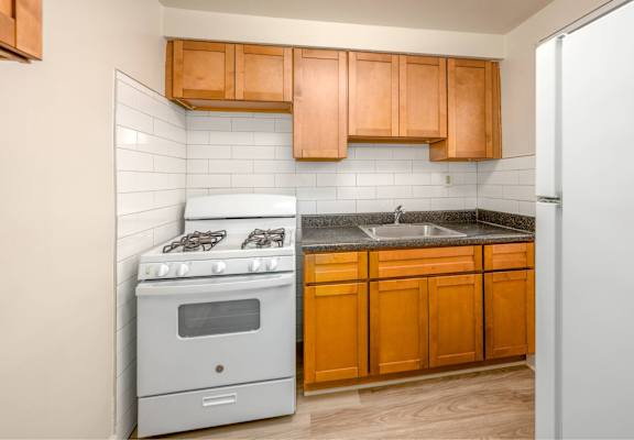 A kitchen with a stove, sink, and cabinets.