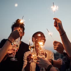 people celebrating with sparklers at a party with wine glasses