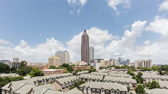 A cityscape with a tall building in the background and apartment buildings in the foreground.