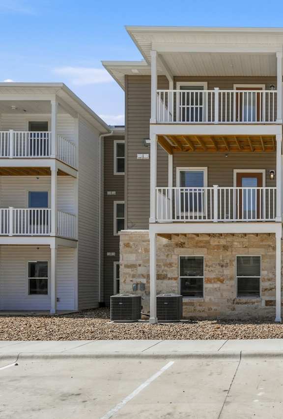 A row of modern townhouses with balconies and a mix of stone and siding exteriors.