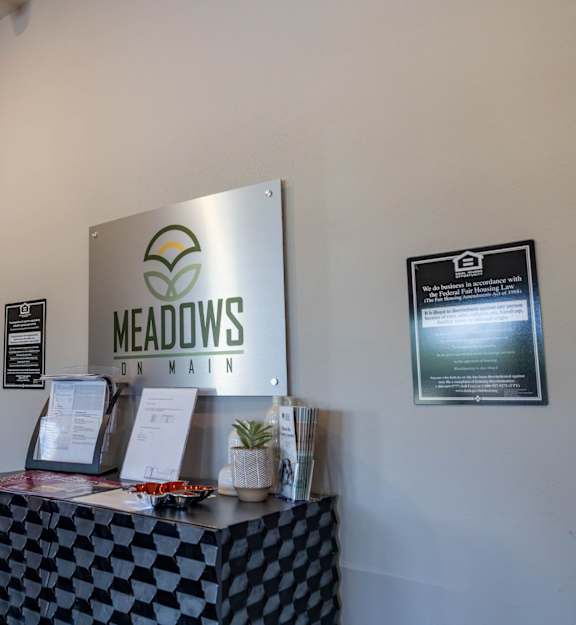 A sign that says Meadows on it hangs on a wall.