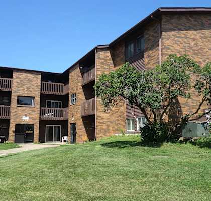 A large brick building with a green lawn in front.