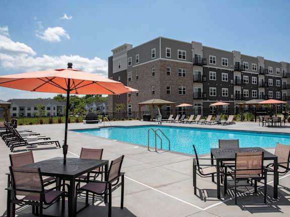 A pool area with chairs and umbrellas in front of a building.at The Edison at Woodbury, Woodbury Minnesota